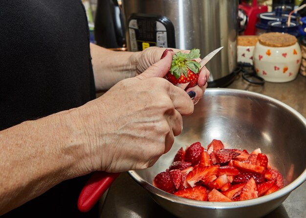 Chef corta morangos para sobremesa na cozinha de casa