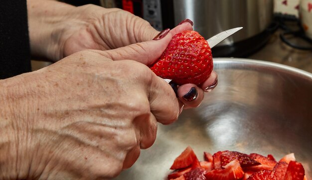 Chef corta morangos para sobremesa na cozinha de casa