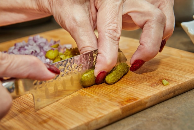 Chef corta pepinillos con cuchillo para preparar todo según la receta