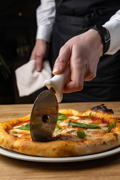 Un chef corta una pizza con un cuchillo.