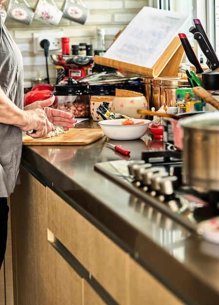 Chef corta queijo na cozinha de casa para cozinhar de acordo com uma receita da internet