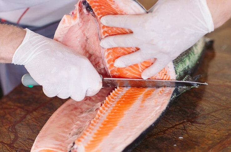 El chef corta el salmón en la mesa.