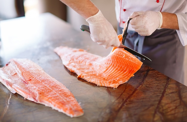 El chef corta el salmón sobre la mesa.