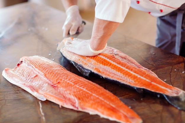 El chef corta el salmón sobre la mesa.