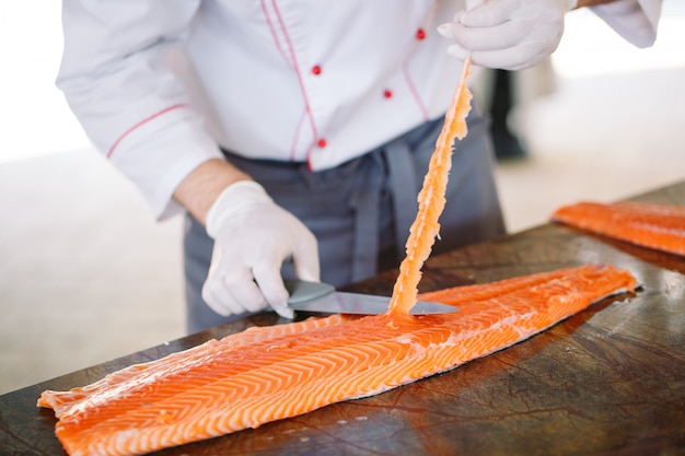 El chef corta el salmón sobre la mesa.