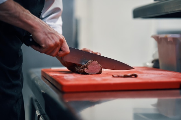 Chef cortando bife na cozinha profissional