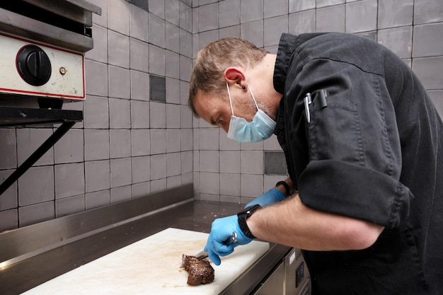 Chef cortando bistec jugoso en una placa en la cocina comercial