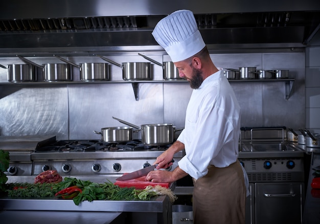 Chef cortando carne en restaurante de cocina