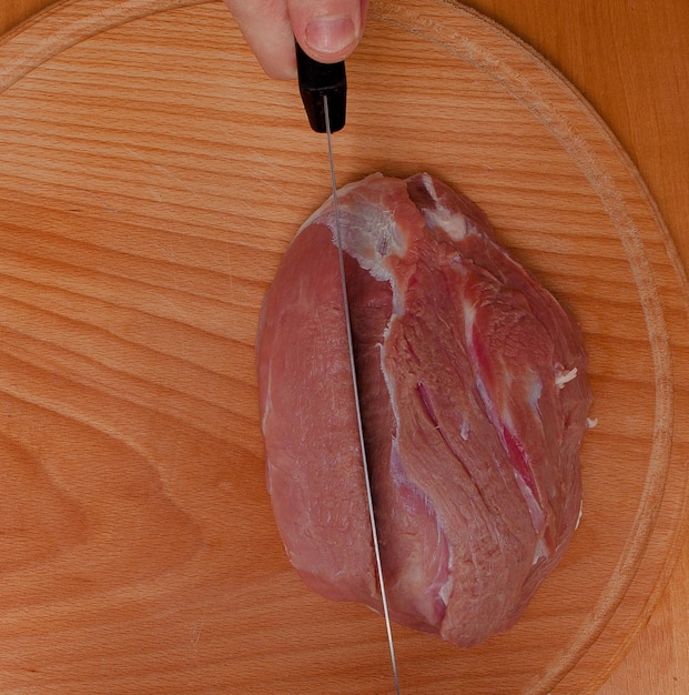 El chef cortando la carne en una tabla de madera