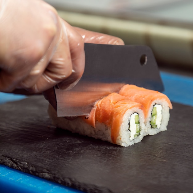 Chef cortando o rolinho de sushi light da Filadélfia de perto