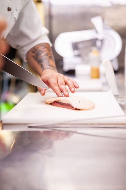 Chef cortando peito de pato no restaurante da cozinha. Preparação de carne