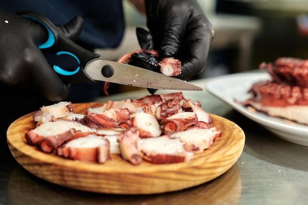 Chef cortando polvo cozido em um prato redondo de madeira