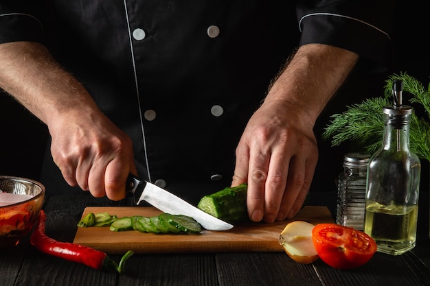 Chef cortando um pepino verde na cozinha de um restaurante