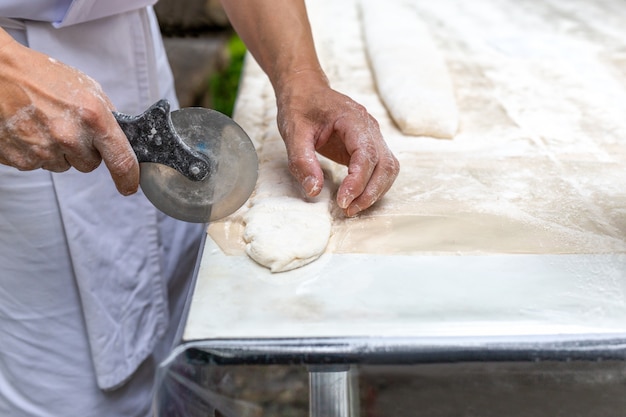 Chef cortar un pastel con un cuchillo de pizza en la mesa