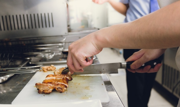 Chef cortar pollo a bordo con un cuchillo