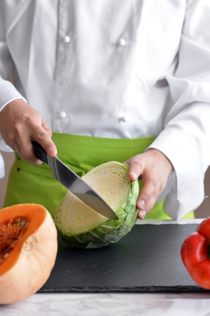 Chef cortar verduras en la mesa para cocinar