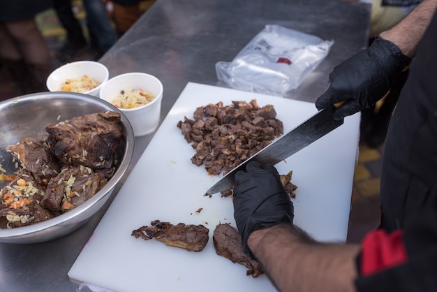 Chef cozinha carne de ovelha na rua