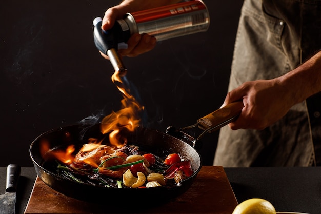 Chef cozinha com fogo em uma panela de camarão com legumes