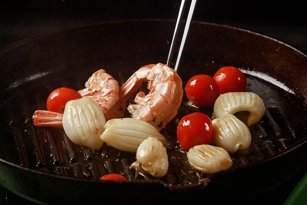 Chef cozinha frutos do mar, camarão em uma panela com legumes