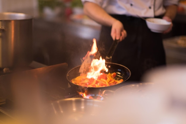 Chef cozinhando e flambando em comida na cozinha do restaurante