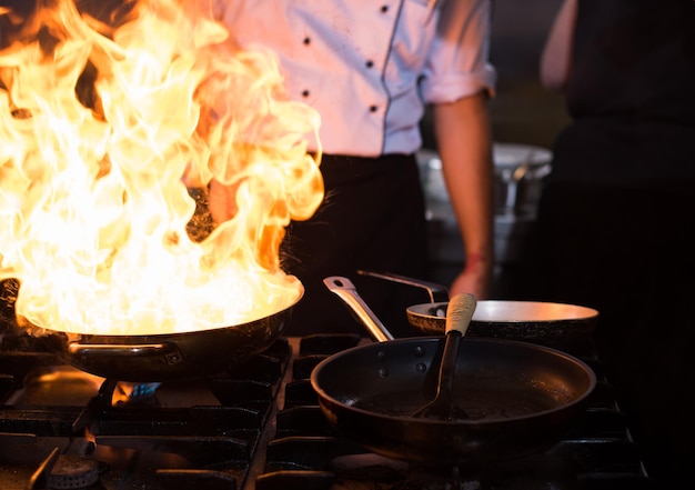 Chef cozinhando e flambando em comida na cozinha do restaurante