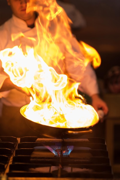 Chef cozinhando e flambando em comida na cozinha do restaurante