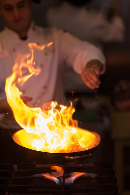 Foto chef cozinhando e flambando em comida na cozinha do restaurante