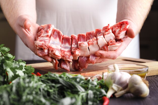 Chef con un cuchillo en la mano corta carne fresca en una mesa