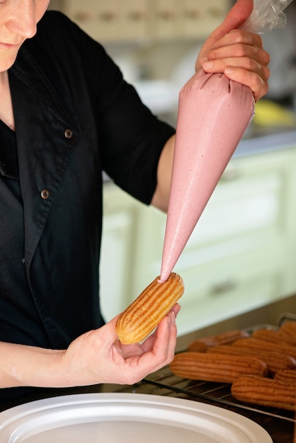 Chef de confeitaria enche os éclairs de creme de perto