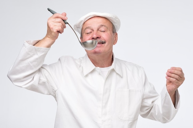 Chef de cozinha masculino em uniforme branco, degustação de comida de concha
