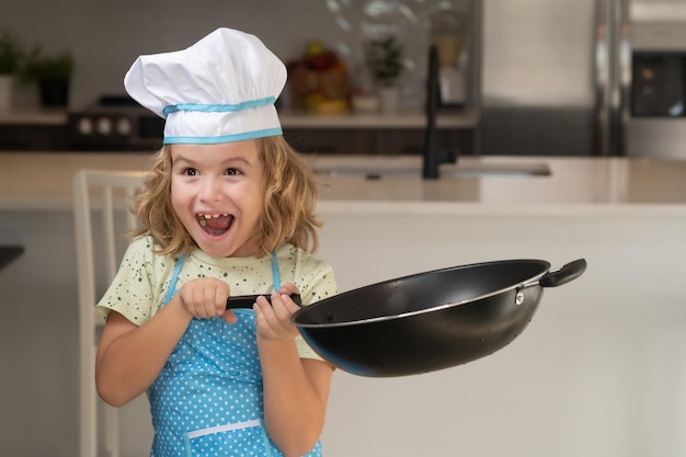 Chef de criança cozinha culinária com panela na cozinha Chef de criança cozinha com chapéu de chef preparando comida na cozinha Criança fazendo saborosa e deliciosa refeição