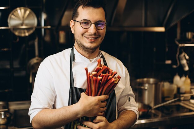 Chef de homem segurando ruibarbo na cozinha