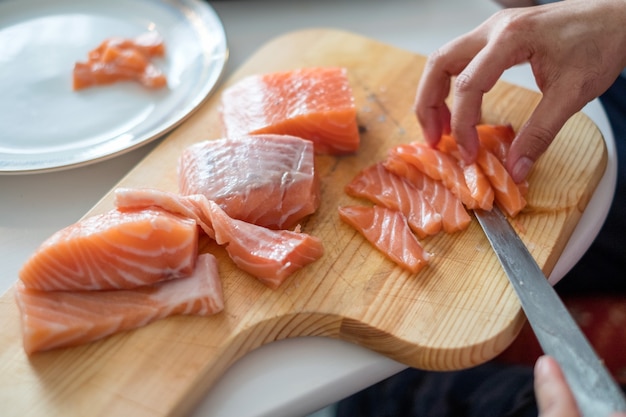 Chef de mão usando uma fatia de faca de salmão cru na tábua de cortar