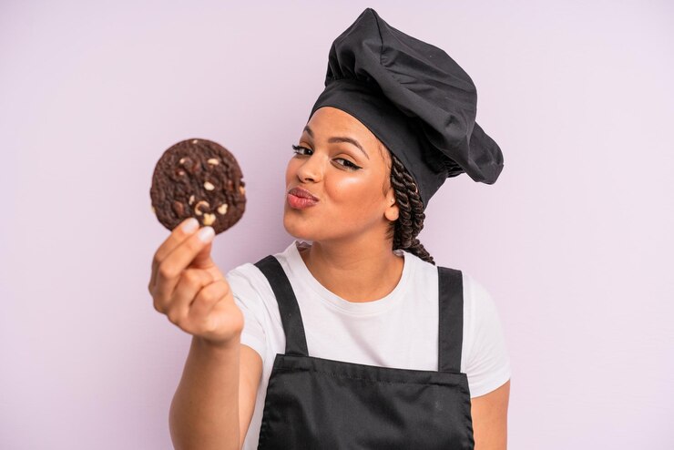 Foto chef de mulher negra afro com tranças e fazendo um biscoito