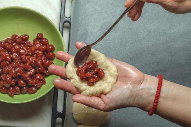 Chef de pastelaria coloca uma colher de cereja na massa de pão preparada