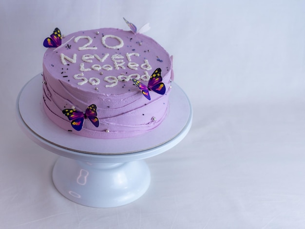 Chef de pastelaria decorando um bolo de aniversário fosco roxo com cobertura de texto polvilha pérolas e borboletas