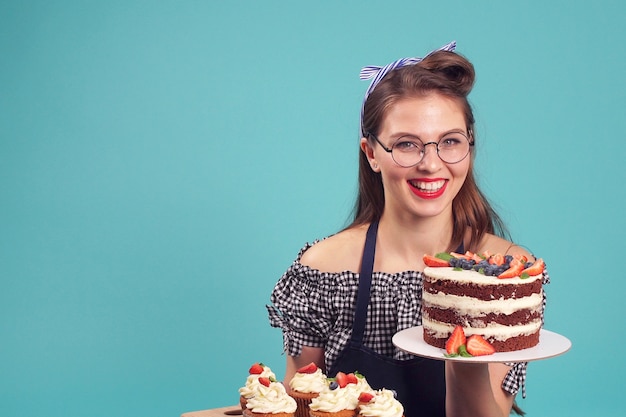 Chef de pastelaria feliz posando para a câmera com um bolo nas mãos