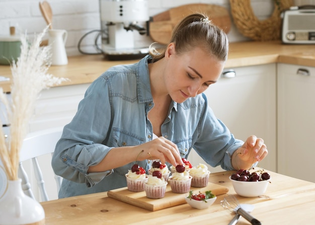 Chef de pastelaria jovem decora cupcakes com frutas