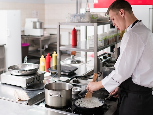 Chef de pé na cozinha de um restaurante e cozinhando uma refeição. Um profissional no trabalho.