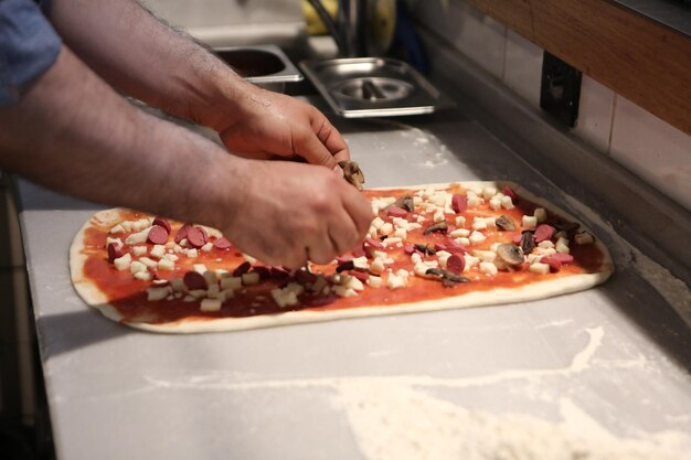 Chef de pizza colocou molho na base em uma cozinha comercial