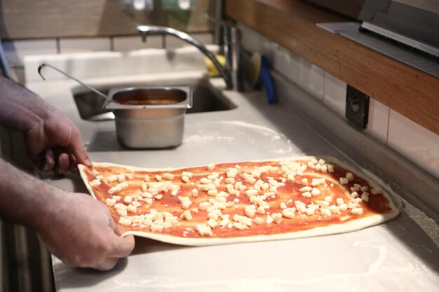 Chef de pizza colocou molho na base em uma cozinha comercial