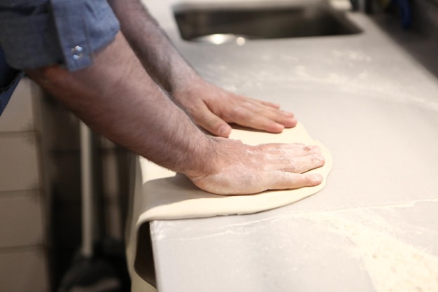 Chef de pizza colocou molho na base em uma cozinha comercial