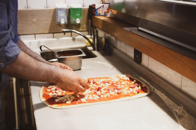 Chef de pizza colocou molho na base em uma cozinha comercial