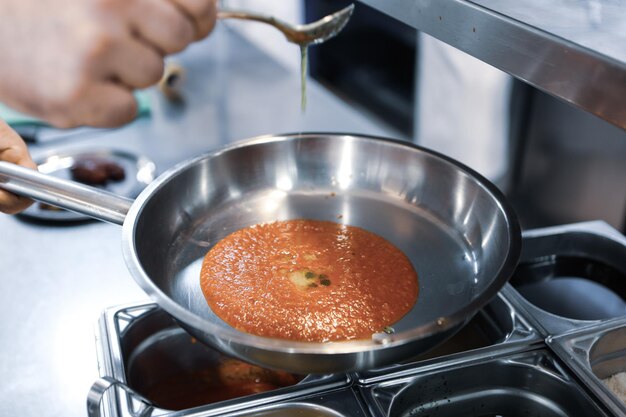 Chef de pizza colocou molho na base em uma cozinha comercial