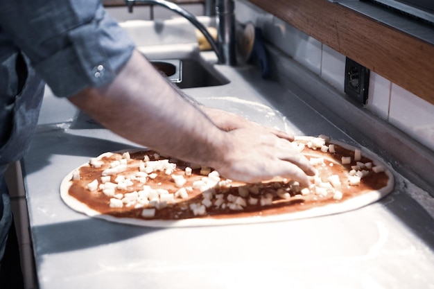 Chef de pizza colocou molho na base em uma cozinha comercial