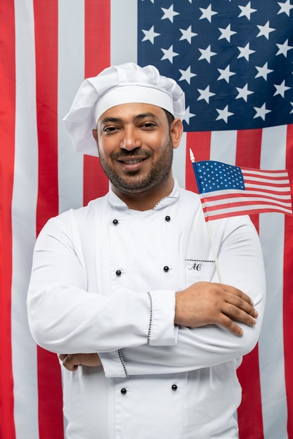 Foto chef de restaurante bem sucedido com os braços cruzados no peito segurando a bandeira