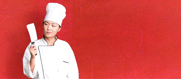Chef de restaurante jovem adulto bonito mulher asiática com uma faca