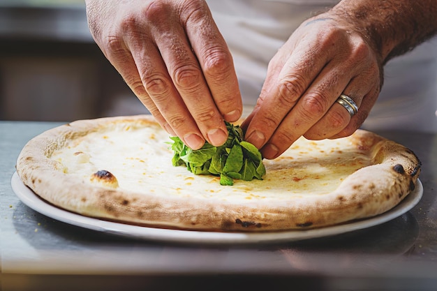 Chef decorando uma pizza italiana com legumes rucola closeup nas mãos comida típica italiana e conceito de bebida