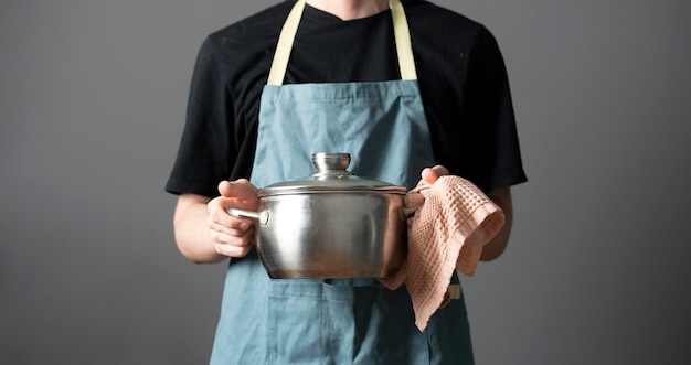 Un chef en delantal cocinando un plato sosteniendo una olla en la cocina