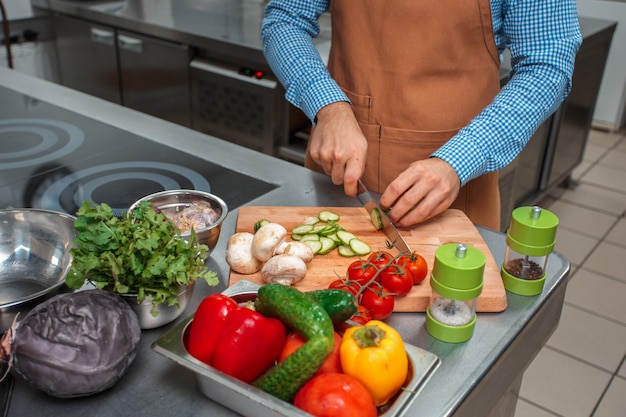 Foto el chef en delantal marrón cocinando en la cocina de un restaurante